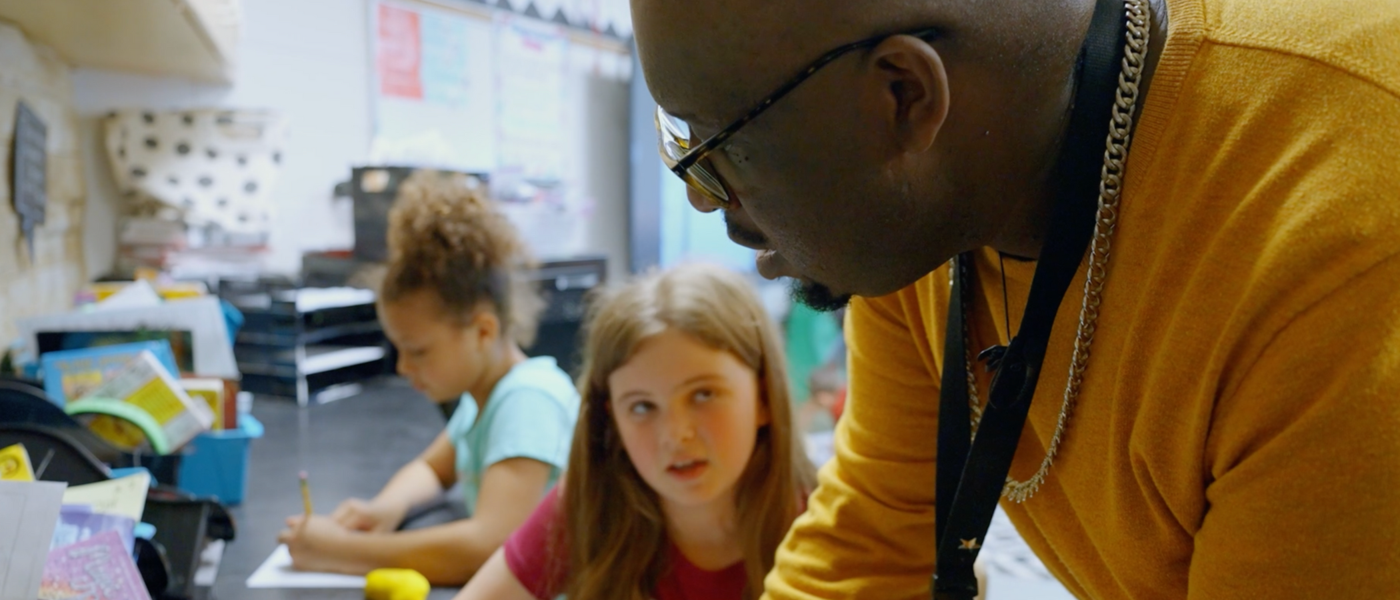 An adult staff member helps a student