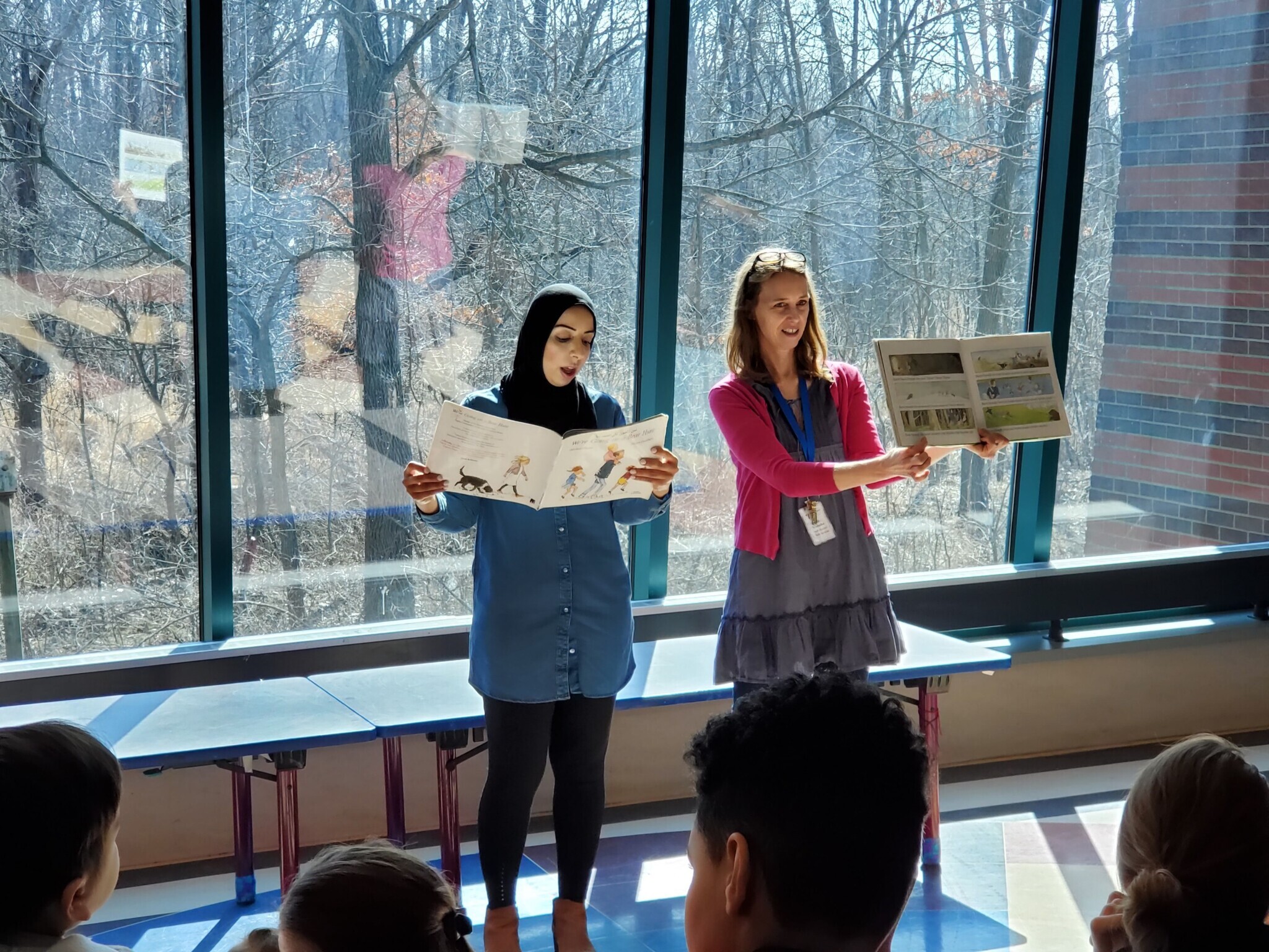 Two adult women read books to small children